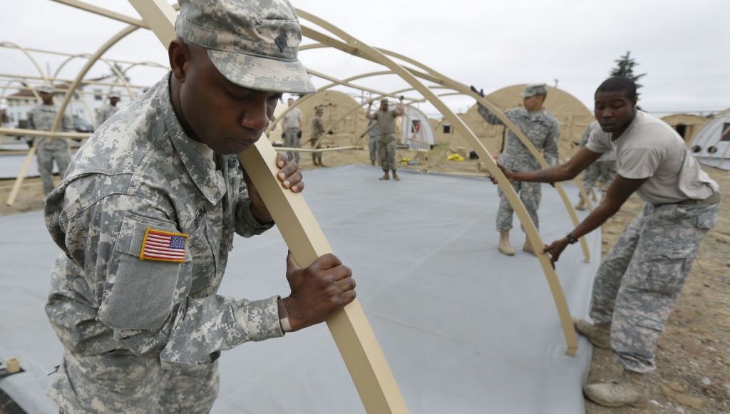 U.S. Army Spc. Apase Ibrahim (left) of Fort Eustis in Newport News, Virginia, helps assemble temporary living structures at Joint Base Lewis-McChord on May 24.