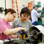 Precision machining instructor Jennifer Perrault, left, helps Rachel Howbert set up for making texture patterns for a vice handle at Everett Community College&rsquo;s Advanced Manufacturing Training & Education Center. The college opened AMTEC in fall 2014. Programs housed at AMTEC include precision machining, welding and fabrication, engineering technician, composites and pre-employment programs. (Andy Bronson / The Herald)