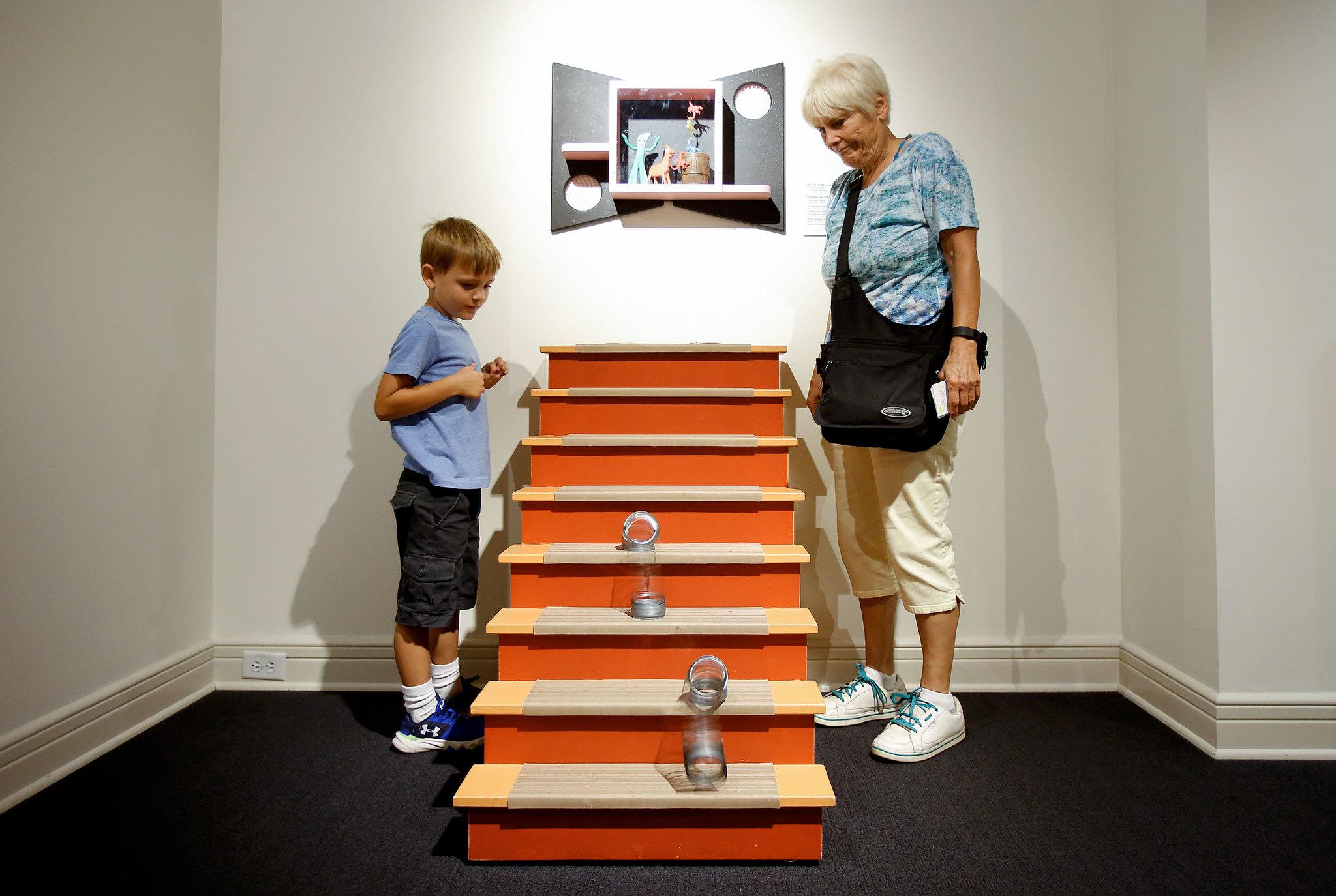 Kai Quaale, 6, and his grandmother, Cindy Andre, race Slinkies down a staircase at the West Coast premiere of Toys of the &rsquo;50s, &rsquo;60s and &rsquo;70s exhibit in the Museum of History & Industry in Seattle. The exhibit is scheduled through Sept. 25. ( Andy Bronson / The Herald )