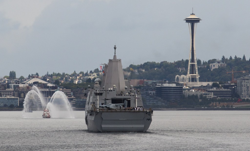The Chief Leschi fireboat sprays water ahead of the USS Somerset as it enters Elliott Bay in Seattle on Tuesday. (Andy Bronson / The Herald)