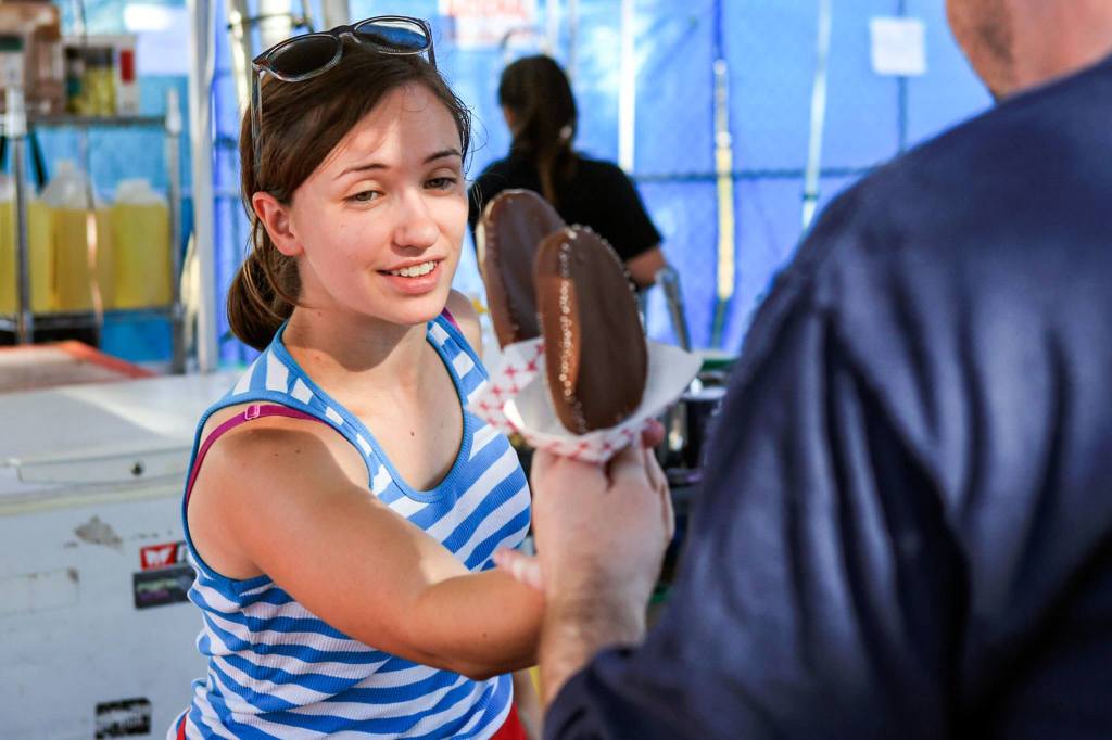 Marcy Daniels passes over ice cream treats during the annual of Taste of Edmonds on Friday afternoon in downtown Edmonds. (Kevin Clark / The Herald)