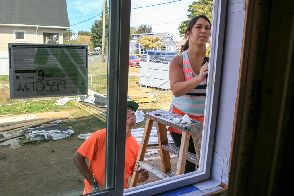 Kevin Clark / The Daily Herald                                Ray Flores watches his wife, Sandra Flores, caulk the window trim of their new home. The couple must put in 500 hours of sweat equity on the house, which is scheduled to be completed in December.