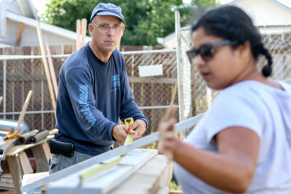 Del Guess (left) takes a measurement with Taniya Bhowal at the site of Sandra and Ray Flores&rsquo; new home Saturday morning in Everett. (Kevin Clark / The Daily Herald)