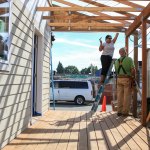 Volunteer Taniya Bhowal works on the back porch with Chris Anderson looking on at Sandra and Ray Flores&rsquo; new home Saturday morning in Everett. (Kevin Clark / The Daily Herald)