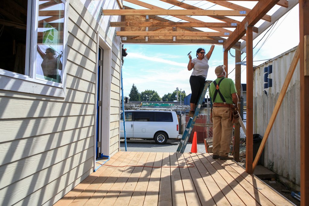 Volunteer Taniya Bhowal works on the back porch with Chris Anderson looking on at Sandra and Ray Flores&rsquo; new home Saturday morning in Everett. (Kevin Clark / The Daily Herald)
