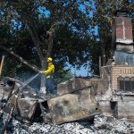 Dan Peters, with the Nevato Fire District, mops up a fire at a house during the Clayton fire after structures were destroyed in Lower Lake, California, on Monday. (Hector Amezcua/The Sacramento Bee via AP)