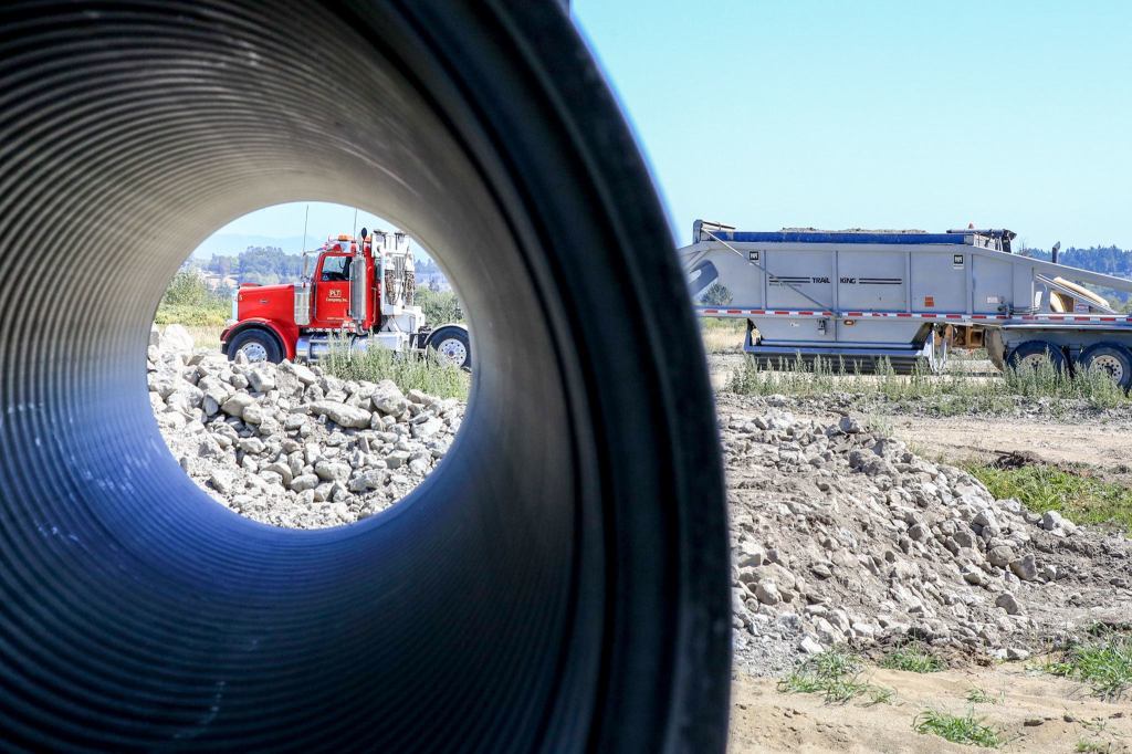 A truck delivers clean fill as work continues to reshape and extend the levee on Smith Island in Everett. (Kevin Clark / The Herald)