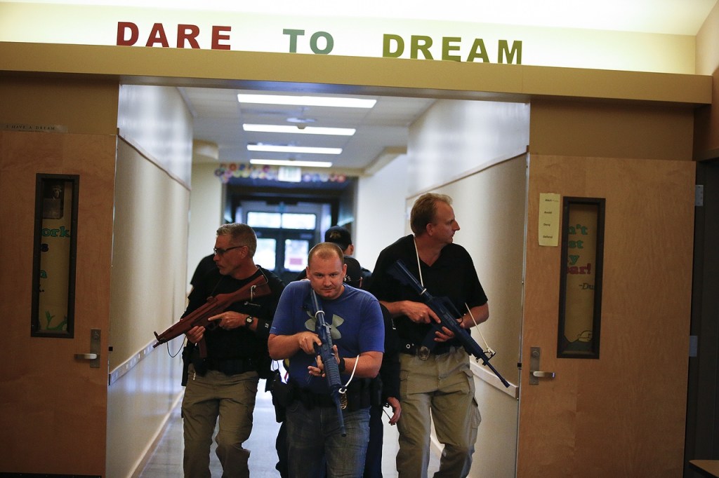 Marysville Police officers maneuver down a hallway at Grove Elementary School in Marysville during a training exercise meant to teach law enforcement how to properly escort paramedics into hostile environments on Aug. 9. The teams, consisting of four officers and two firefighters, are taught to move quickly and to not expose themselves in doorways and other openings for more than a few seconds at a time. (Ian Terry / The Herald)