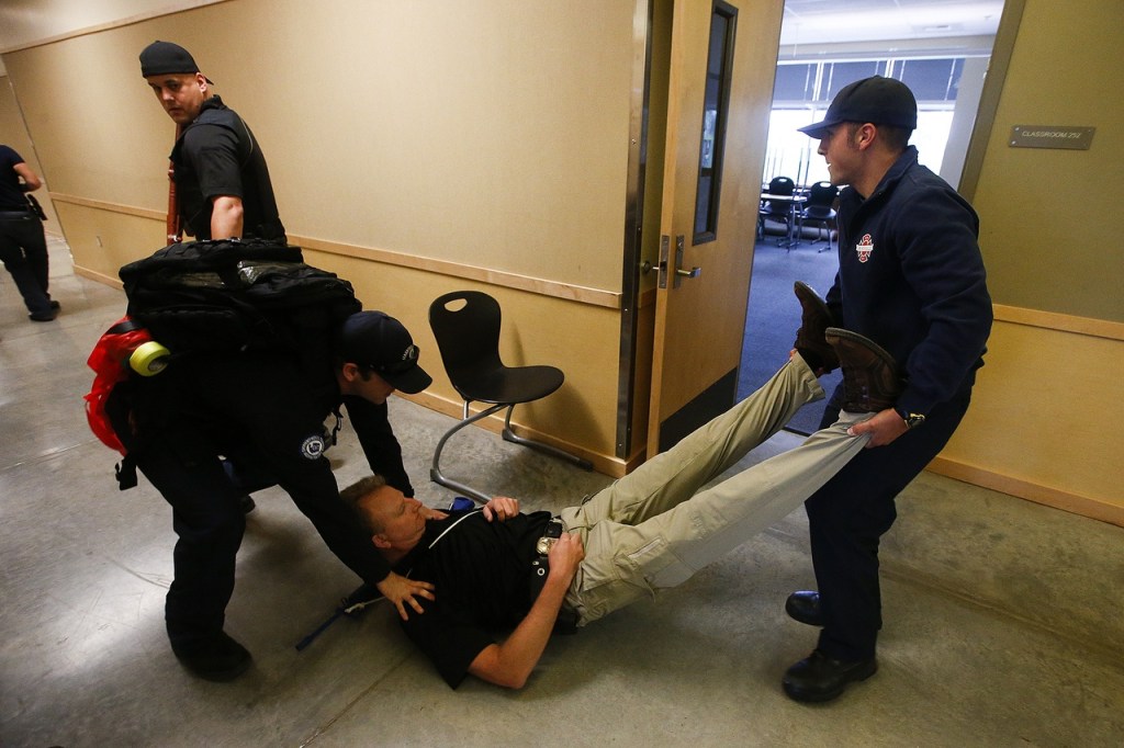 Marysville firefighters carry Marysville Police Detective Darryn Wiersma to safety during a training exercise at Grove Elementary School on Aug. 9. (Ian Terry / The Herald)