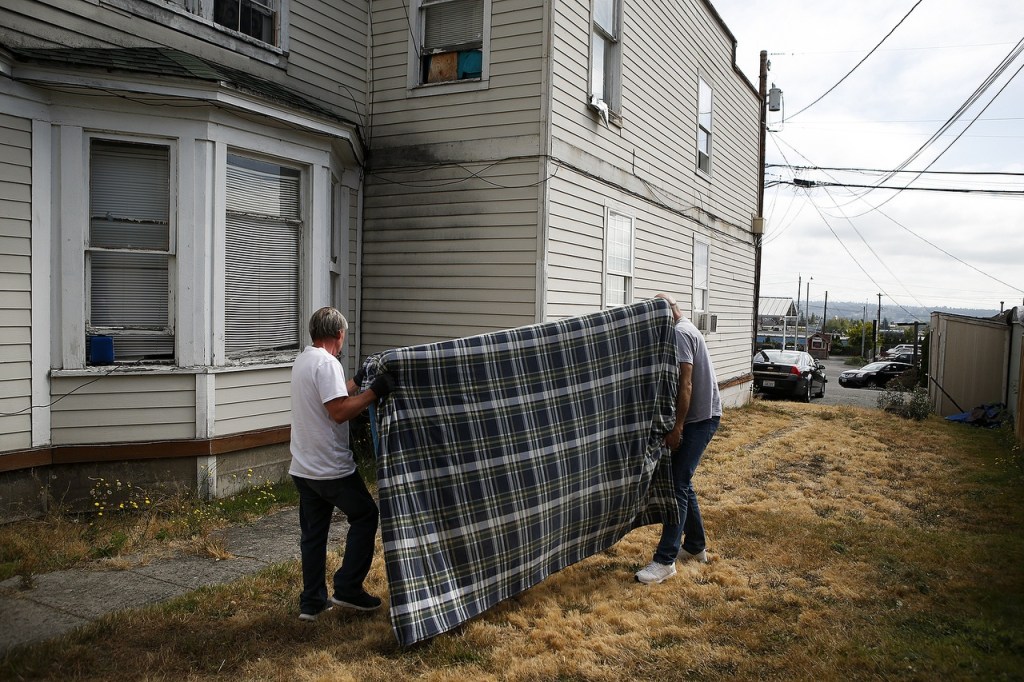 A man&rsquo;s mattress is carried away after he was evicted from a room in a house on Lombard Avenue in Everett on Aug. 11. (Ian Terry / The Herald)