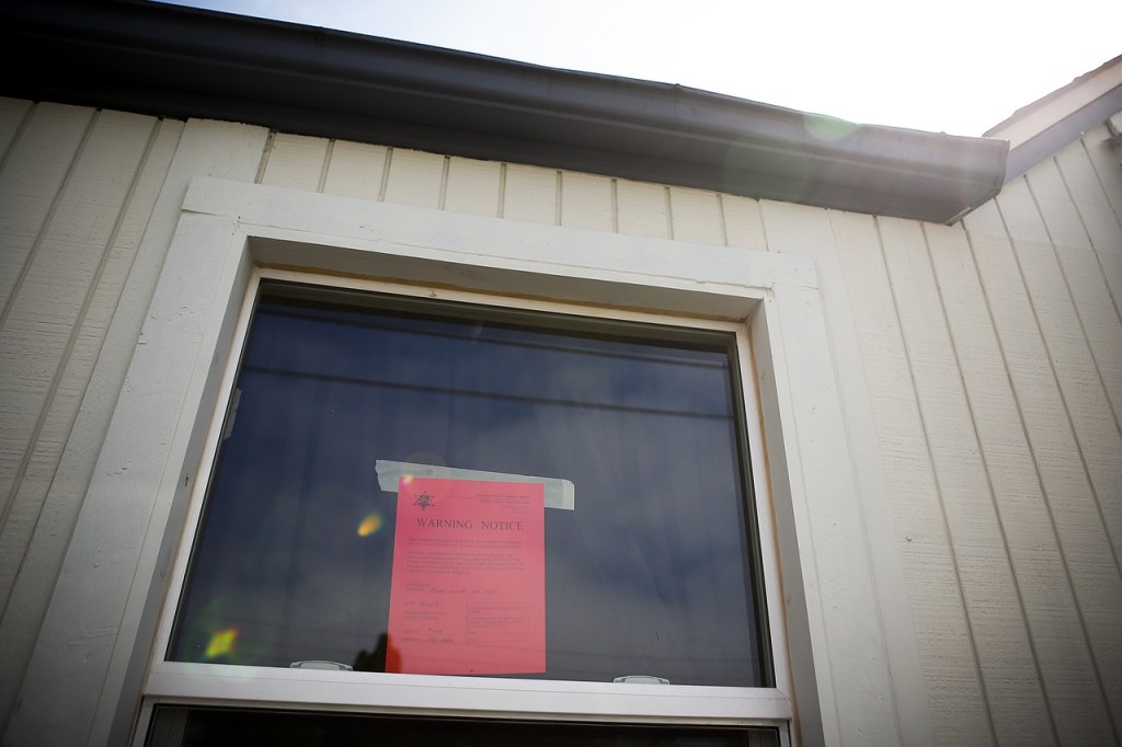 A warning notice is seen in a window after being placed there to deter trespassers by a Snohomish County sheriff&rsquo;s deputy on Aug. 11. (Ian Terry / The Herald)