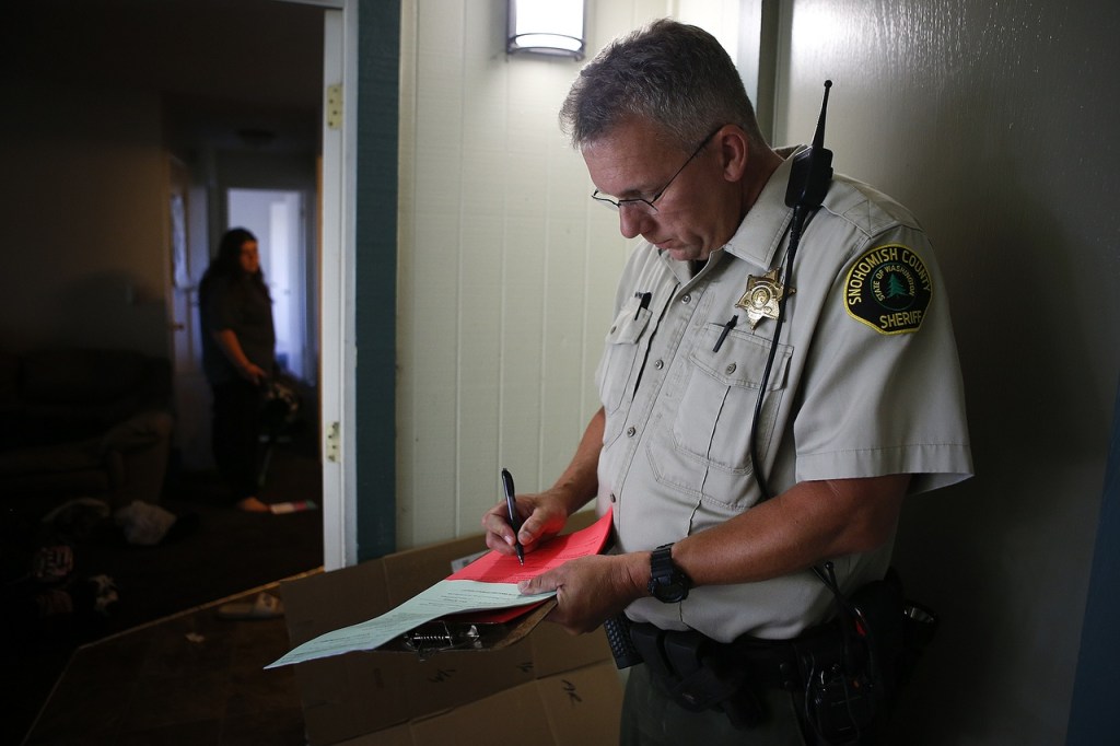 Snohomish County sheriff&rsquo;s deputy Randy Winkley fills out paperwork during an eviction at an apartment in south Everett on Aug. 11. (Ian Terry / The Herald)