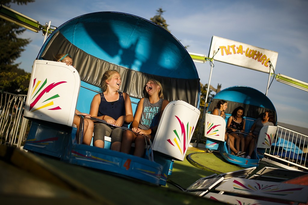 Kaylee Maki (center), 12, of Monroe, screams as she rides the Tilt-A-Whirl with her cousin Geena Mattila, 11, and sister McKenna Maki, 11, at the second day of the Evergreen State Fair in Monroe on Friday evening. (Ian Terry / The Herald)