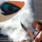 Linda Soriano of the Lummi Nation performs a smudge ceremony at Saint Mark&rsquo;s Episcopal Cathedral in Seattle, fanning smoke from burning sage with eagle feathers onto a totem pole, on Thursday. The 22-foot-tall Lummi Nation totem pole is traveling nearly 5,000 miles across the U.S. and Canada to galvanize opposition to the development of fossil fuel infrastructure, particularly around sea ports in Oregon and Washington. (AP Photo/Manuel Valdes)