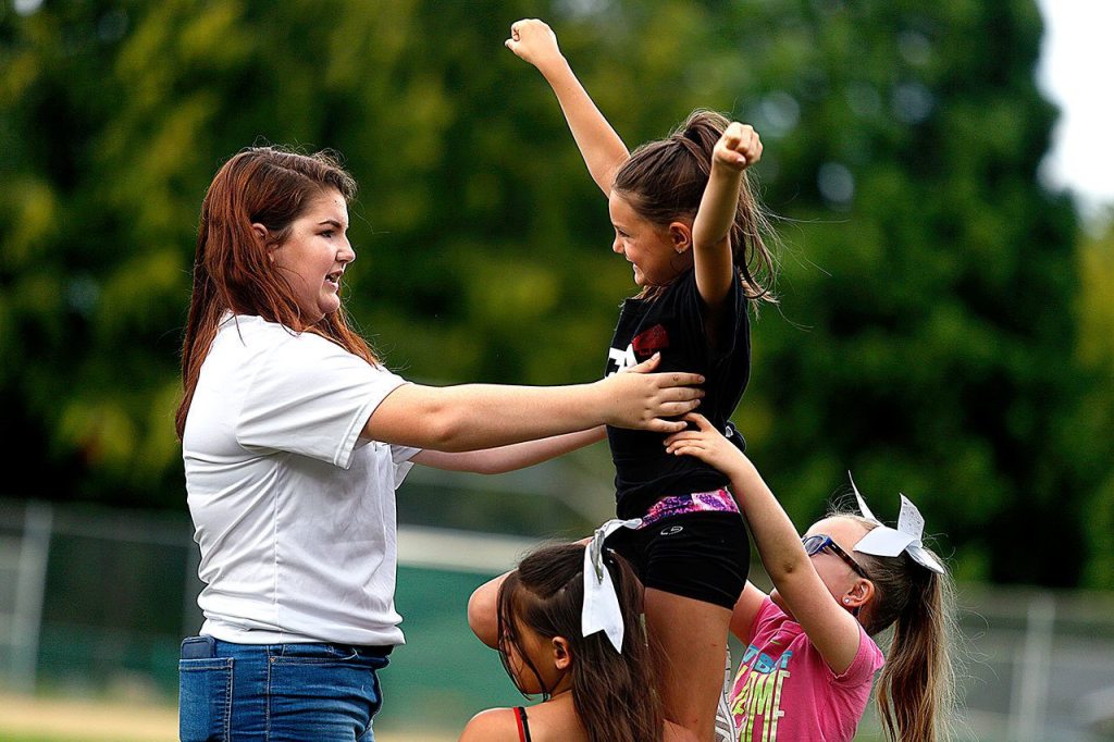Cassie Kunselman, 15, holds Amaya Villalobos, 7, up high, while she is supported in a cheer technique by Alawna Schweitzberger, 11 (lower left) and Jaelyn fox, 7 during a practice session at Jennings Park in Marysville. (Dan Bates / The Herald).