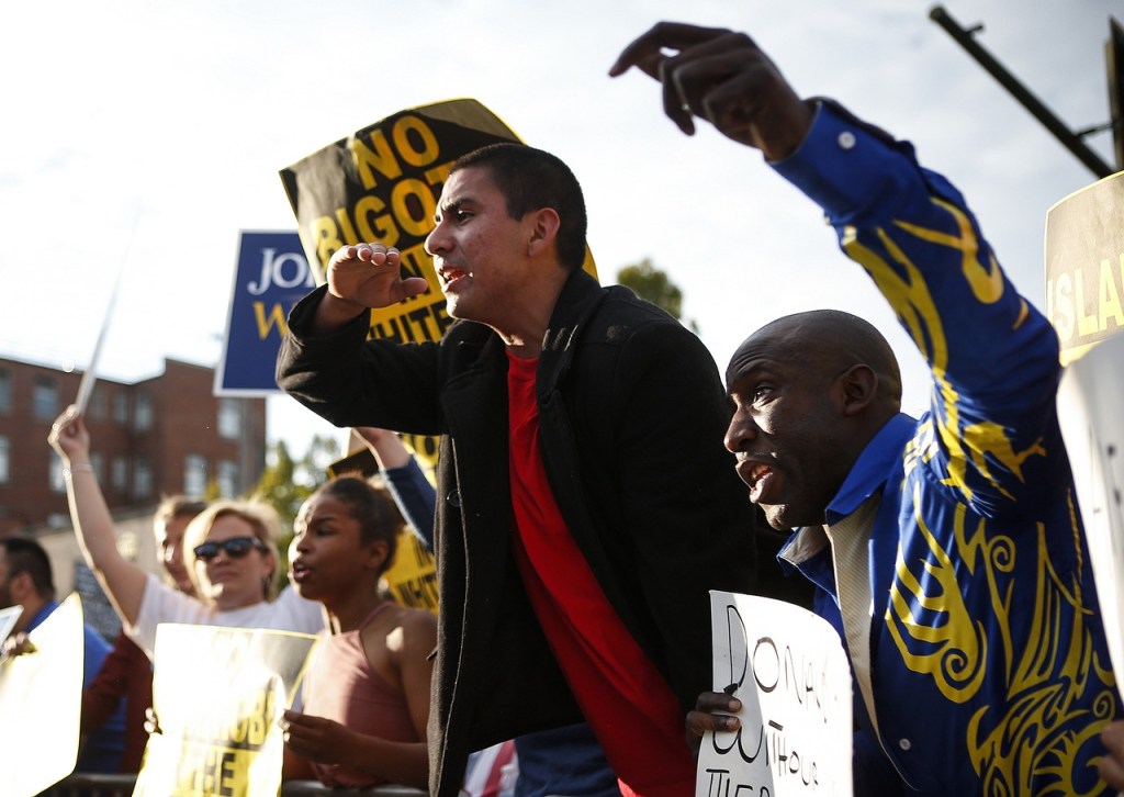 Protesters Sergio Landin (center), of Everett, and Babaja Bahu (right), of Lynnwood, yell at Donald Trump supporters before a rally for the Republican presidential nominee at Xfinity Arena on Tuesday. (Ian Terry / The Herald)