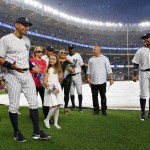 Alex Rodriguez reacts to a sudden thunderstorm during a pregame ceremony final game with the New York Yankees on Friday in New York. Rodriguez is joined by his two daughters, Natasha and Ella, his mother, and Yankees shortstop Didi Gregious (center rear) and second baseman Starlin Castro (far right). (AP Photo/Kathy Willens)