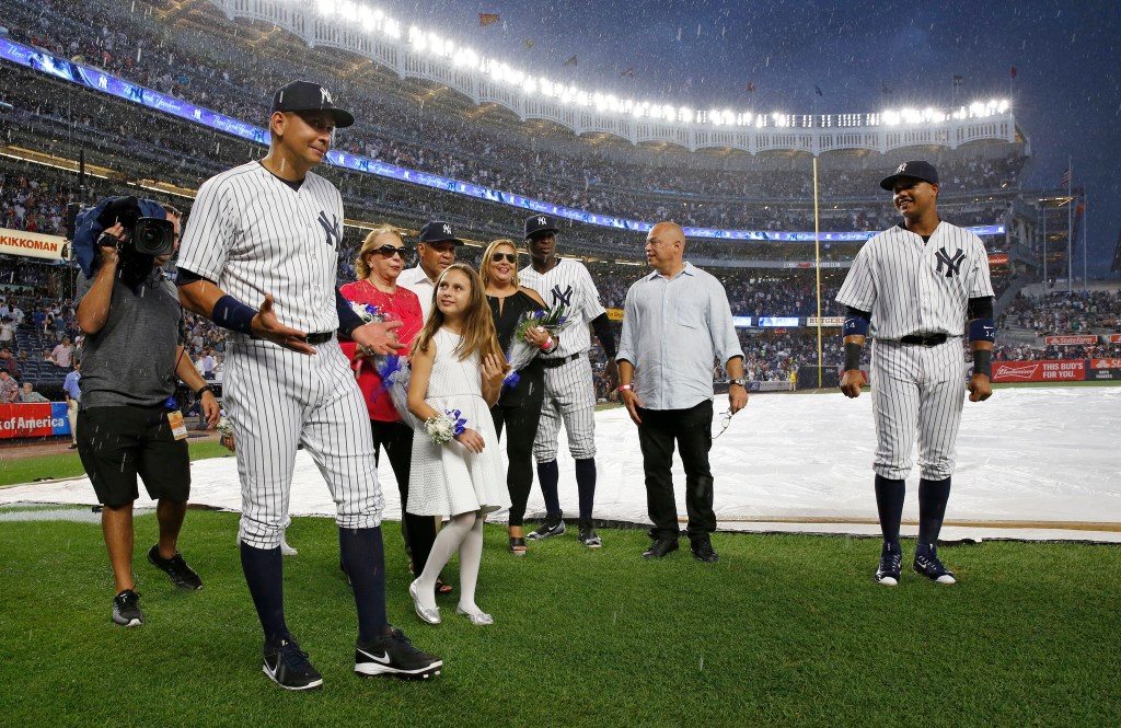 Alex Rodriguez reacts to a sudden thunderstorm during a pregame ceremony final game with the New York Yankees on Friday in New York. Rodriguez is joined by his two daughters, Natasha and Ella, his mother, and Yankees shortstop Didi Gregious (center rear) and second baseman Starlin Castro (far right). (AP Photo/Kathy Willens)