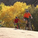 Mountain bikers climb up the rock in Moab National Park.