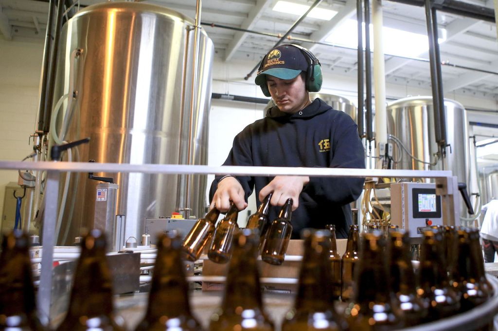 Mickey Ponte stacks bottles for labeling and filling at Scuttlebutt Brewery in Everett.
