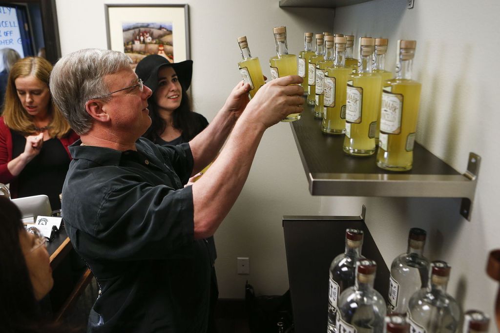 Brian Senff (left), of Kent, helps Alisa Andonian stock shelves full of Temple Distilling&rsquo;s new Bookmark Limoncello liqueur during its release party.