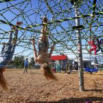 Friends Layla Taylor (left), 11, and Amberle Peterson, 10, hang upside down Monday on a new climbing attraction at the Henry M. Jackson Park in Everett.