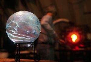Mark Ellinger heats glass in his Stanwood studio in 2010. On a table in front of him is a glass float for the Great Northwest Glass Quest.