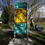 Snohomish resident Laura Stutz walks past used street signs that have been converted into interpretive signs that, on the other side, display tidbits of information about the county’s history along the Centennial Trail in Snohomish. The signs are part of a bigger project called Past Forward.