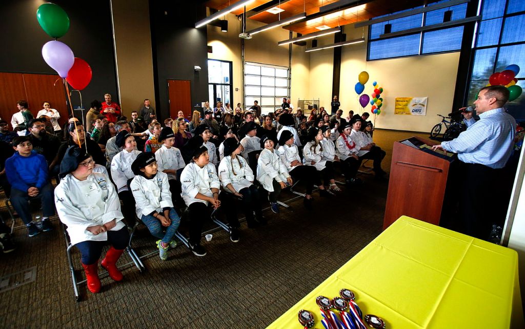 In the main event room, the 22 elementary school cooks sit in two rows for the awards presentation, which was kicked off by nutrition services manager, Brad Wall at right.