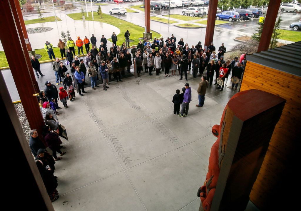 Master carvers James Madison (purple), sons Jayden, 10, and Jevin, 8, and Joe Gobin address a crowd Monday morning at the unveiling of two story poles at the Tulalip Tribes administration building.