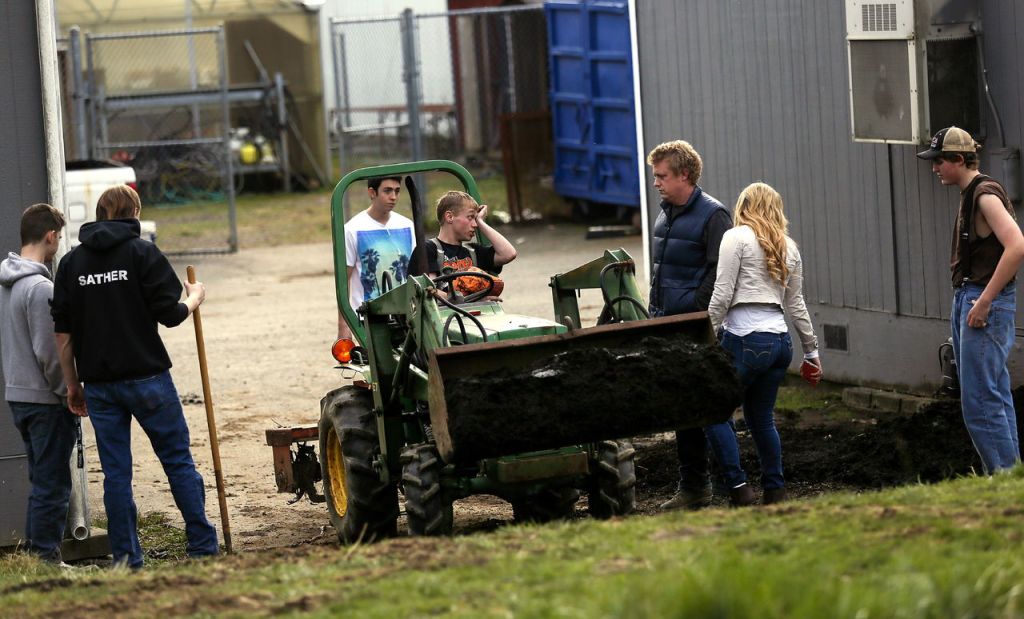 At the edge of the acreage being developed by students behind the school, Advanced Biology teacher Ryan Monger talks with student tractor driver Cole De Isle as other students deliver planting mix to a site being developed as a tree museum. Monger teaches &ldquo;Green Sustainables and Design and Tech.&rdquo;