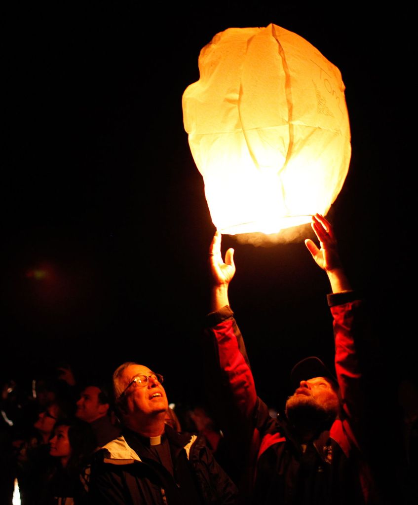 The Rev. Tim Sauer looks on as Nathan Ray releases a lantern into the sky above the Oso mudslide. Families of those lost in the slide gathered a year later to release 43 lanterns, one for each person who died.
