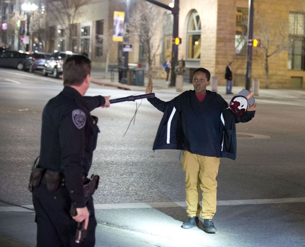 Police stop a boy as he walks away from a crowd that formed after an officer-involved shooting in Salt Lake City on Saturday.