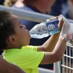 In near record heat, a young baseball fan takes a drink during a Cactus League baseball game between the Cincinnati Reds and the Cleveland Indians on Wednesday in Goodyear, Arizona.