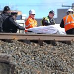 Officials cover the body of one of the people killed in the crash Sunday.
