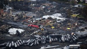 Workers comb through debris July 9, 2013, after a train derailed causing explosions of railway cars carrying crude oil in Lac-Megantic, Quebec. A government watchdog says federal regulators are failing to refer serious safety violations involving freight rail shipments of crude oil for criminal prosecution.
