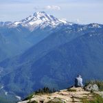 A hiker takes in the view of Glacier Peak from Green Mountain. (Brandon Fralic / For The Herald)