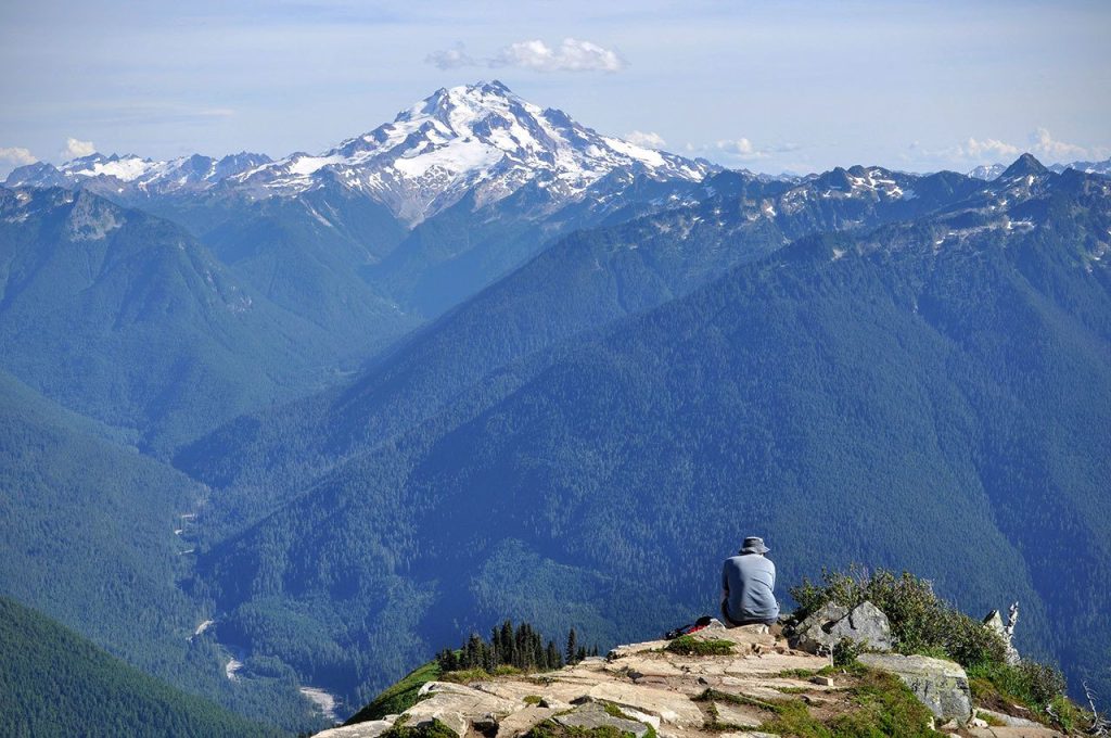 A hiker takes in the view of Glacier Peak from Green Mountain. (Brandon Fralic / For The Herald)