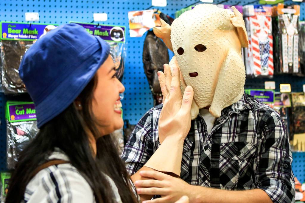 Brittaney Dover, left, of Bellingham pats the masked face of Clifford Goff of Bellingham at the Archie McPhee store. (Kevin Clark / The Herald)