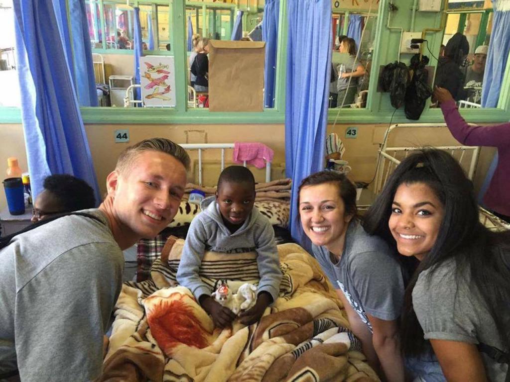 Bethany Christian Assembly teens Sean Lucas (from left), Jackie Huhta and Jael Kilroy visit and give a gift to a boy receiving care at the Mbabane City Hospital during a service trip to Swaziland. A group of teens from the Everett church helped missionary Stan Drew with a variety of projects Aug. 7-17. (Contributed photo)