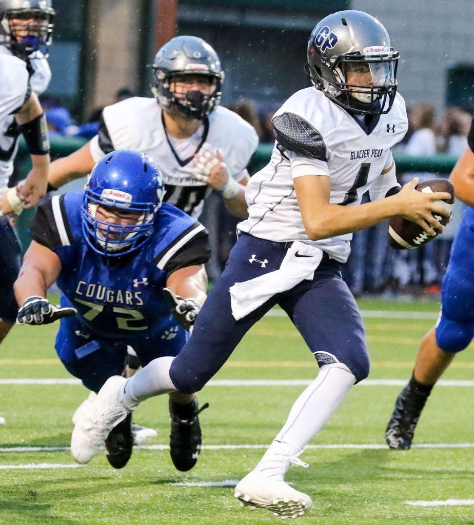Glacier Peak&rsquo;s Ayden Ziomas scrambles to avoid a pass rush by Bothell&rsquo;s Justin Prachar during a game Thursday night at Pop Keeney Stadium in Bothell. (Kevin Clark / The Herald)