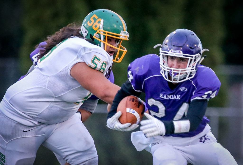 Kamiak&rsquo;s Ben Barton rushes to escape a tackle attempt by Bishop Blanchet&rsquo;s Aarenn Savelio Friday night at Goddard Stadium in Everett. (Kevin Clark / The Herald)
