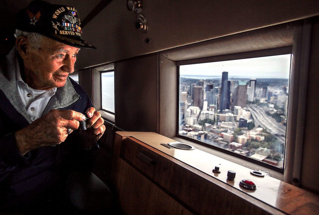 World War II pilot Art Unruh, 93, takes pictures with a miniature camera and gazes at downtown Seattle from the window of the DC-3 before it turns around and heads back toward Everett. (Dan Bates / The Herald)