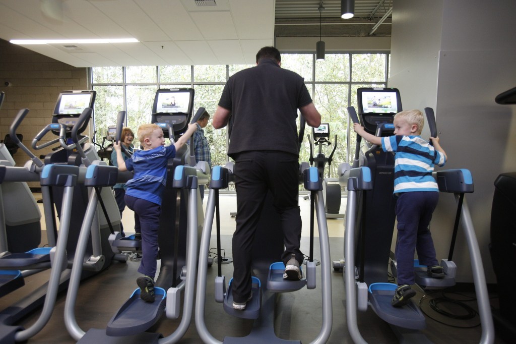 Like father, like sons, Alex and Nick Young, right, imitate their father Jason as they try out exercise equipment at the Grand Opening of the Stanwood-Camano YMCA on Sept. 3, 2016, in Stanwood. (Andy Bronson / The Herald)