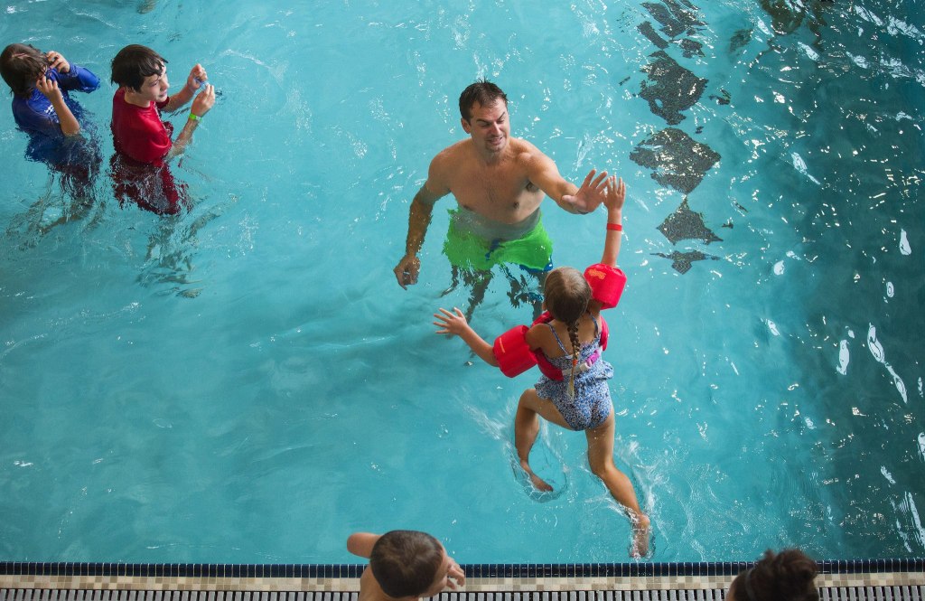 Leaping and reaching out, Braelyn Maus, 5, high fives her father Brad as they play in the pool during the Grand Opening of the Stanwood-Camano YMCA on Sept. 3, 2016, in Stanwood. (Andy Bronson / The Herald)