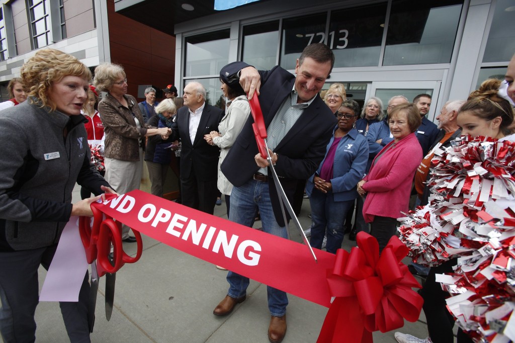 Paul Sobotta, a Cornerstone Donor, uses oversized scissors to cut off a piece of the ribbon for his family at the Grand Opening of the Stanwood-Camano YMCA on Sept. 3, 2016, in Stanwood. (Andy Bronson / The Herald)