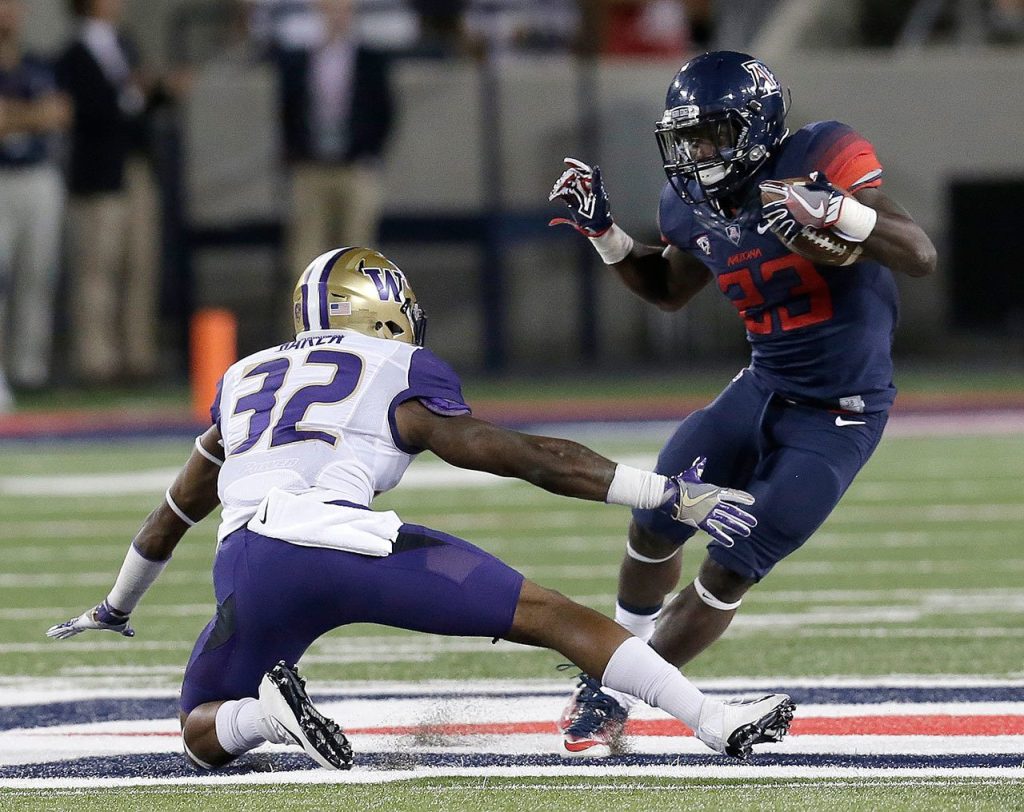Arizona running back J.J. Taylor (23) avoids Washington defensive back Budda Baker during the first half Saturday in Tucson, Ariz. (AP Photo/Rick Scuteri)