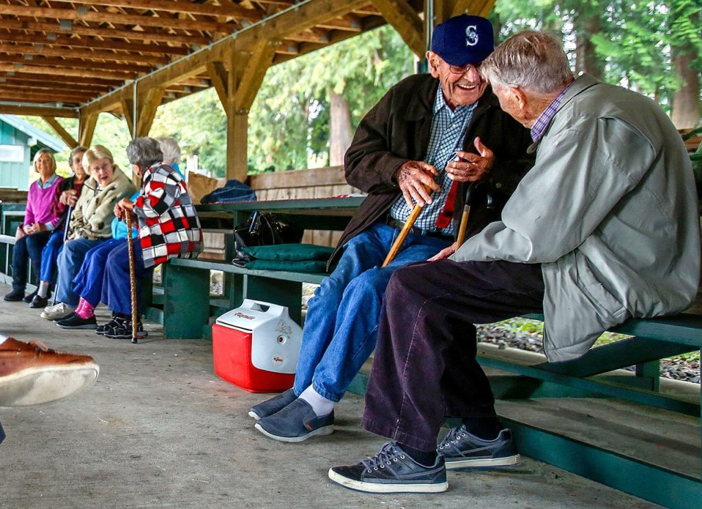While some of the girlhood friends tell stories at a picnic table further down, Glen Allen (facing) bends the ear of Hugh Minor, 91, as the Snohomish High School class of 1942 meets at Hill Park to have lunch and visit during a lively annual class reunion. (Dan Bates / The Herald)