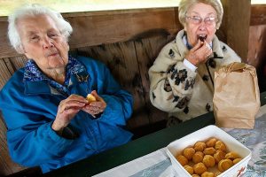 (Dan Bates / The Herald) A pair of 92-year-old Snohomish High School classmates from 1942, Elizabeth Reed (left) and Crystal Johanson appear to be having fun eating what looks to be about 92 Belgian cream puffs during their 74th class reunion at Hill Park, Wednesday.