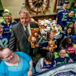 At Shawn O&rsquo;Donnell&rsquo;s Tuesday night, Snohomish County Sea Hawkers Booster Club members and their president, Nina Therres (left #12), squeeze together with Snohomish County Sheriff Ty Trenary (suit and tie) and a whole bunch of cuddly bears for a photograph. They collected the bears to donate, and Sheriff Trenary will be delivering them to Dawson Place, which serves child victims of sexual or physical abuse. (Dan Bates / The Herald)